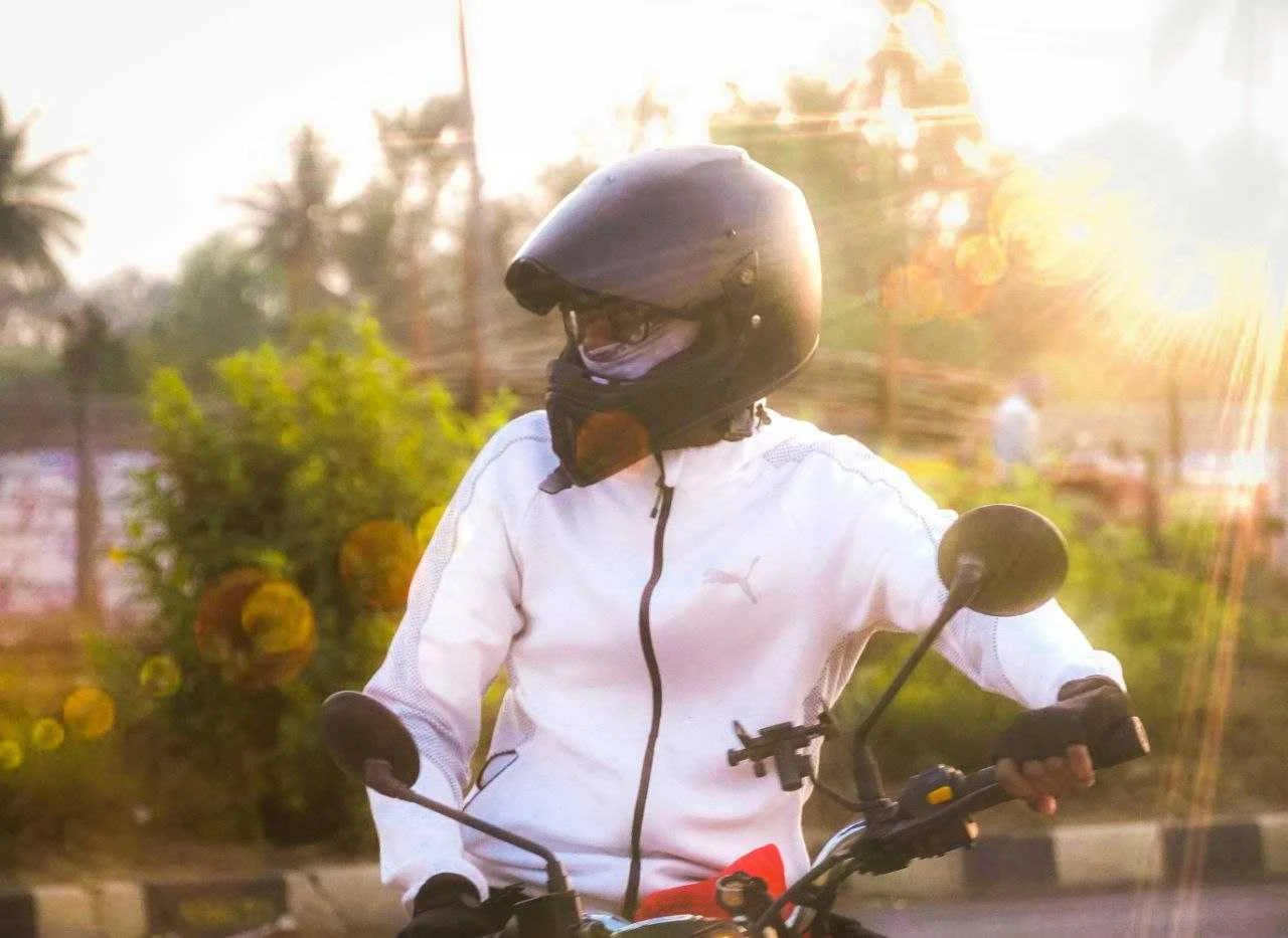 A helmeted motorcyclist in warm late-day light